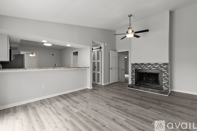 A spacious living room with a fireplace and a ceiling fan.