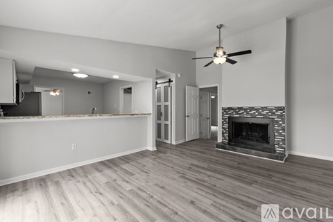 A spacious living room with a fireplace and a ceiling fan.