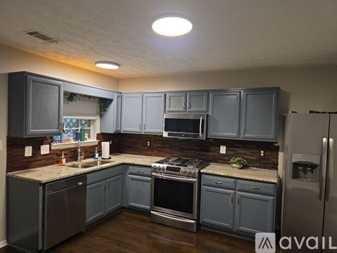A kitchen with a refrigerator, sink, and stove.
