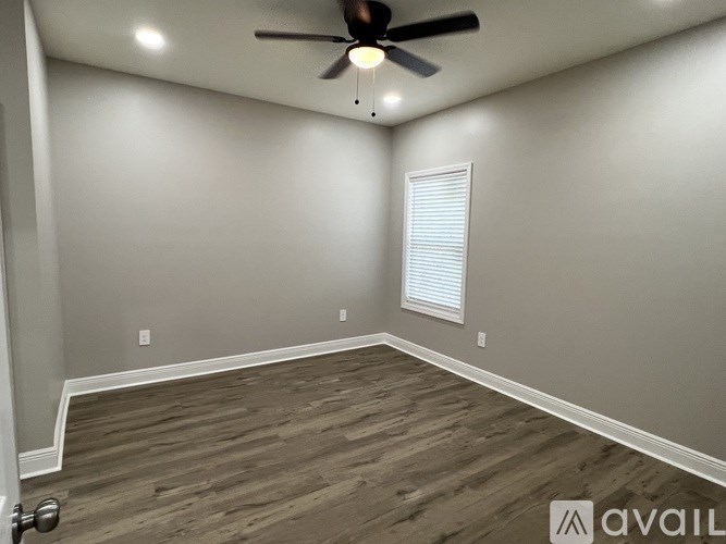 A room with a ceiling fan and a window with blinds.