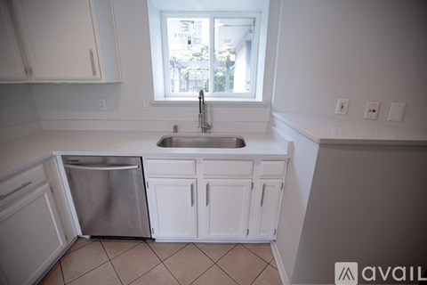 A kitchen with white cabinets and a window above the sink.