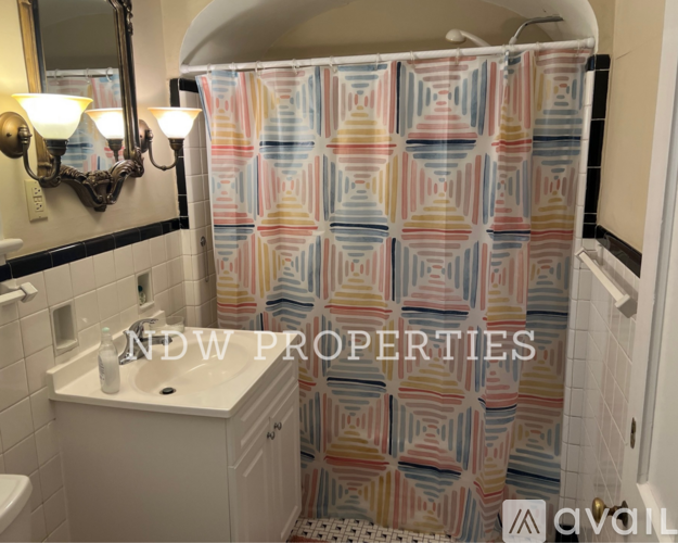 A shower curtain with a geometric pattern in pastel colors hangs in a bathroom.