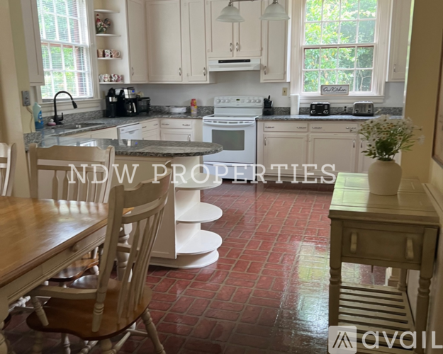 A kitchen with a table and chairs in the foreground and a sign that says "NDW PROPERTIES" in the background.
