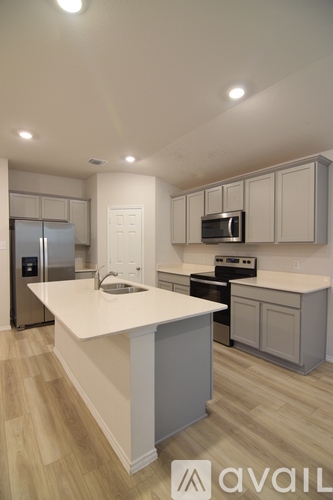 A kitchen with a white countertop and wooden flooring.