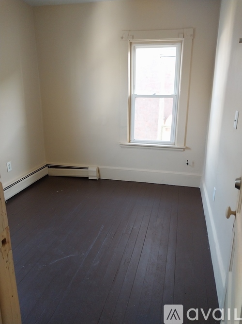 A room with a window and wooden floors.