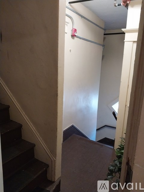 A staircase with a white wall and a door with a pink handle.