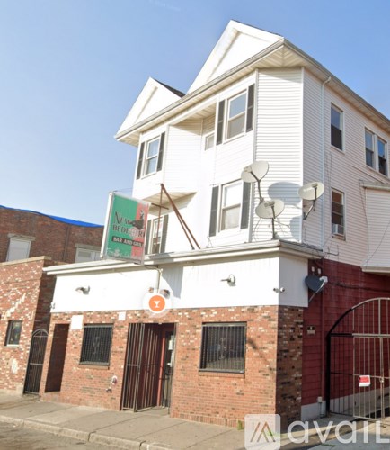 A white two story building with a red gate in front.