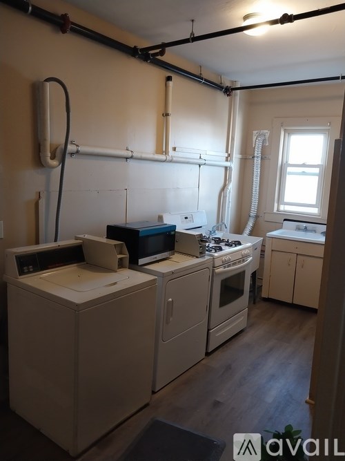 A kitchen with white appliances and wooden floors.