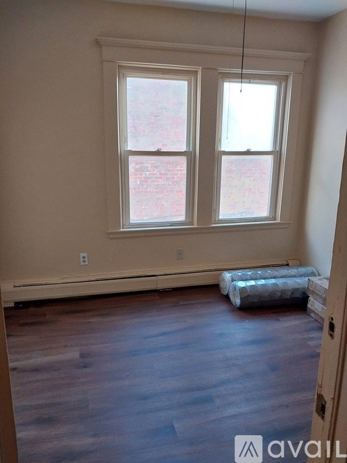 A room with a window and a wooden floor.