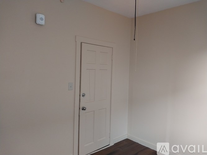 A white door is in a room with a white wall and a white ceiling.