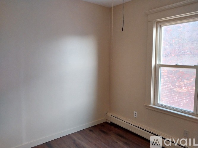 A room with a window and a white wall.