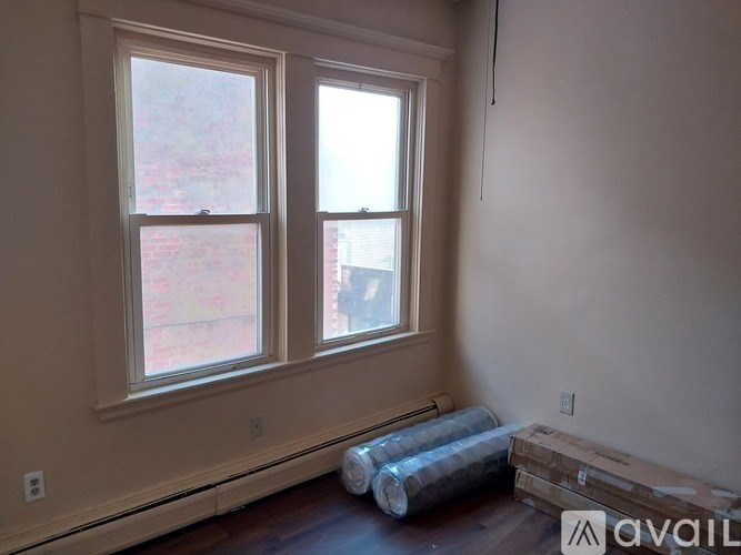 A room with two windows and a wooden floor.