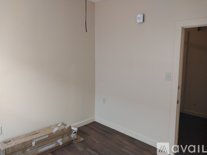 A room with a white wall and a doorway leading to another room.