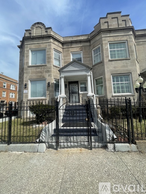 A large, two-story building with a black metal fence in front.