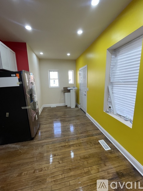 A kitchen with a black fridge and wooden floors.
