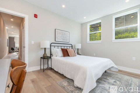 A bedroom with a bed, two lamps, and a chair.