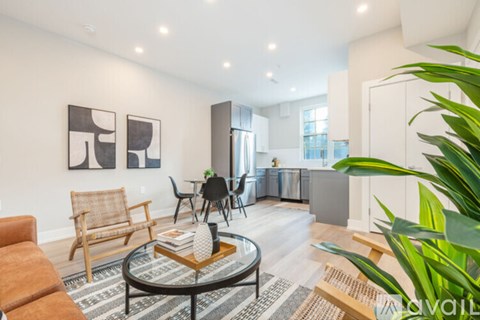 A living room with a coffee table, chairs, and a plant.