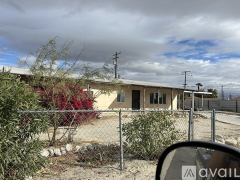 A house with a fence and a sign that says "AVAIL" in the foreground.