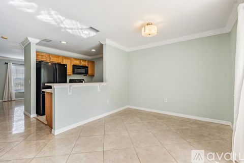 A kitchen area with a black refrigerator and microwave.