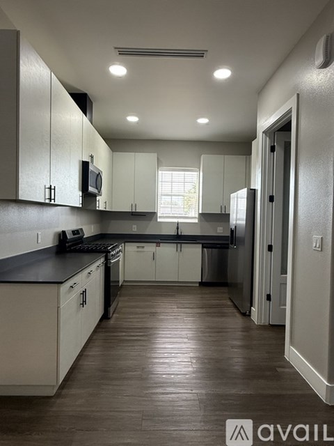 A kitchen with white cabinets and a black countertop.