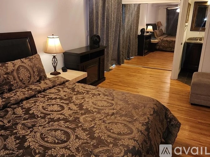 A bedroom with a large bed and a wooden floor.