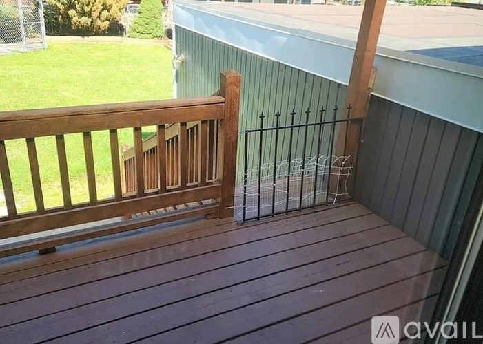 A wooden deck with a railing and a metal fence.