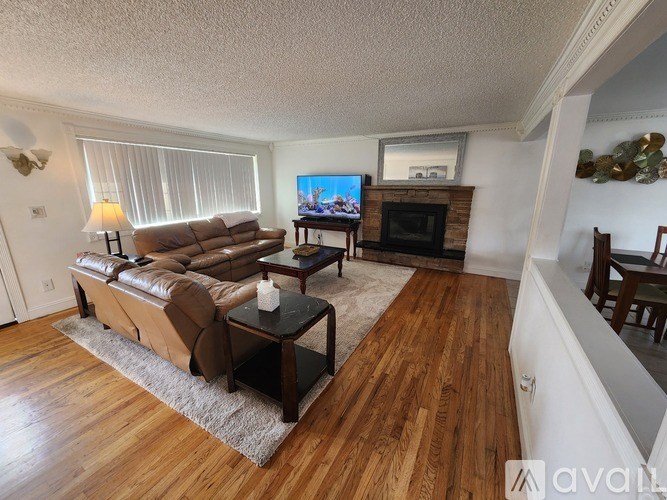 A living room with a brown couch, a coffee table, and a flat screen TV mounted above a fireplace.