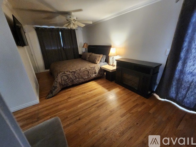 A bedroom with a bed, a nightstand, and a ceiling fan.