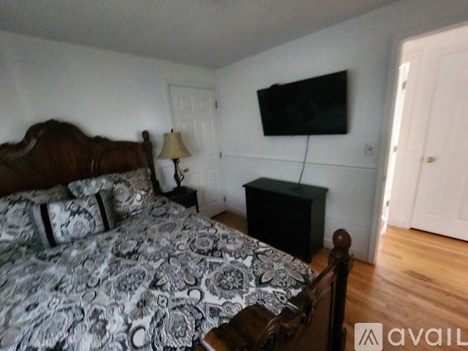 A bedroom with a bed, nightstand, and a television mounted on the wall.