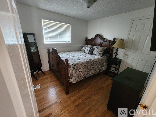 A bedroom with a bed, nightstand, and lamp.