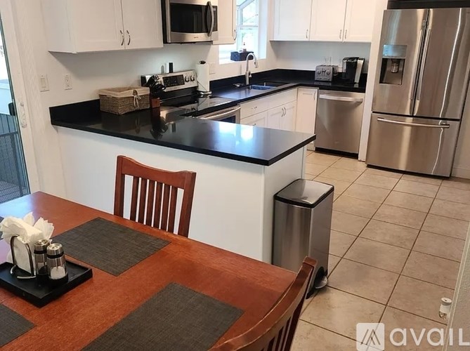 A kitchen with a black countertop and white cabinets.