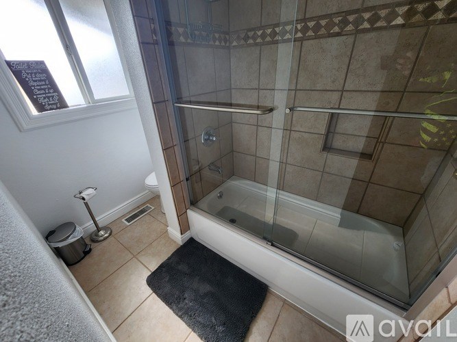 A bathroom with a glass shower door and a white bathtub.