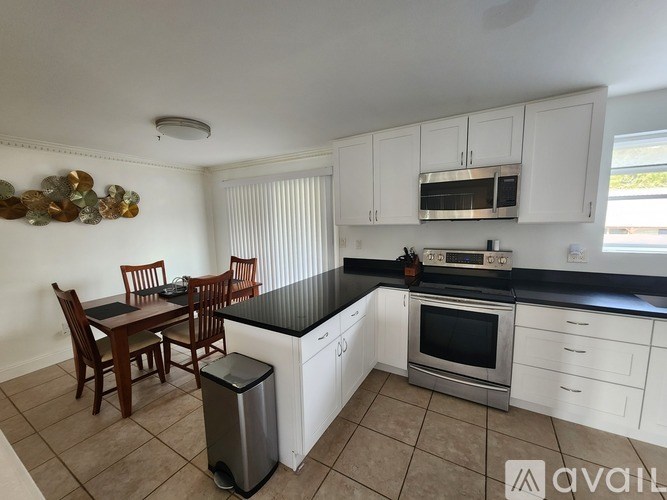 A kitchen with white cabinets and a black countertop.