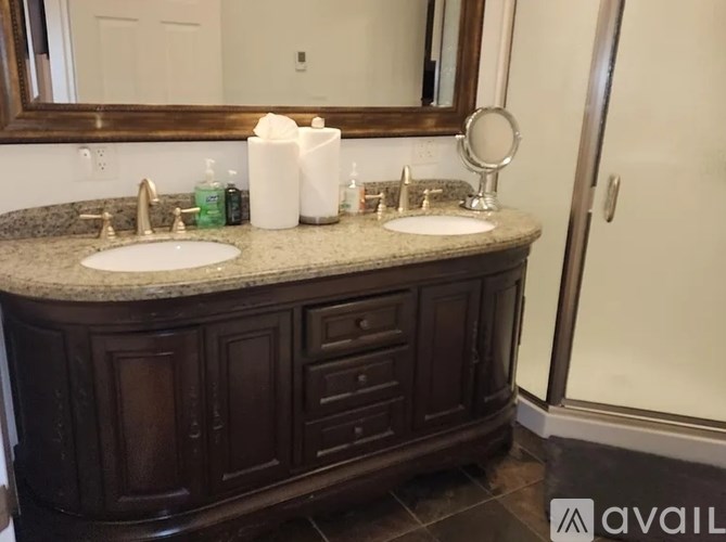 A bathroom with a brown vanity and a mirror above the sink.