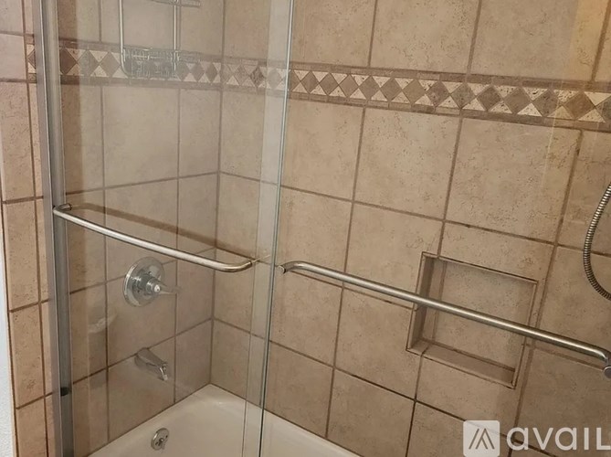 A shower area with a glass door and a glass tile wall.