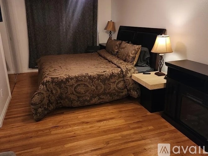 A bedroom with a large bed and a wooden floor.