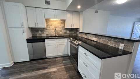 A kitchen with white cabinets and a black countertop.