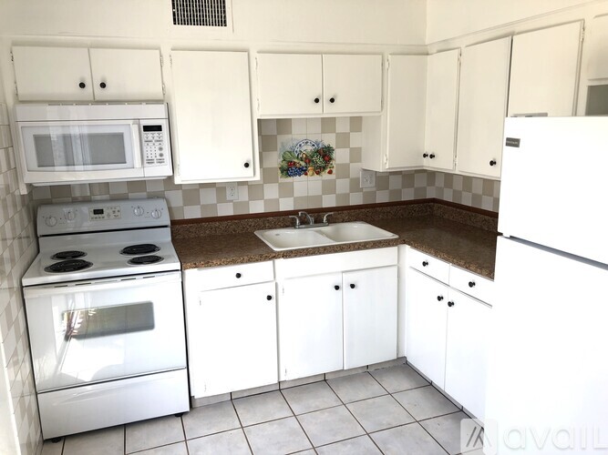 A kitchen with white cabinets and a stainless steel refrigerator.