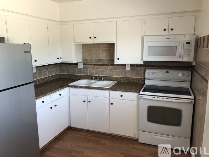 A kitchen with white cabinets and a stainless steel refrigerator.