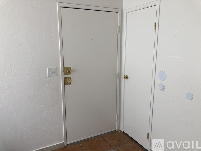 A white door with a gold handle and a white wall.