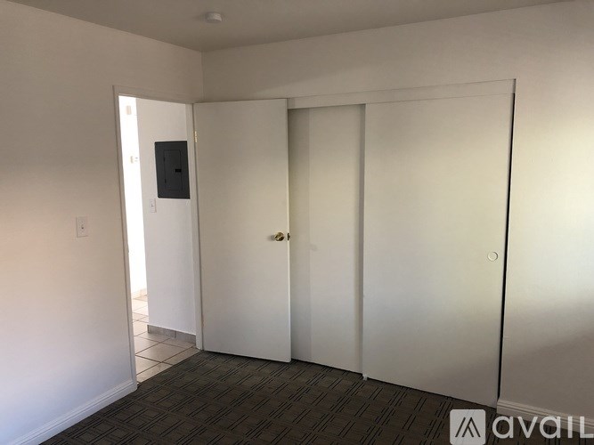 A room with a door, a wall-mounted TV, and a carpeted floor.