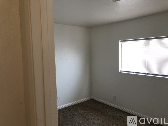 A room with a carpeted floor and a window with blinds.