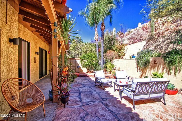 A patio with a chair and a table is surrounded by plants.