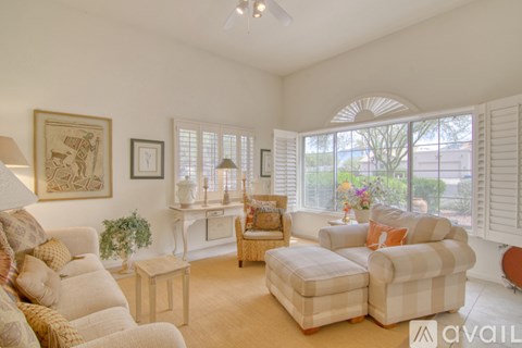 A living room with a white couch, a chair, and a small table with a plant on it.