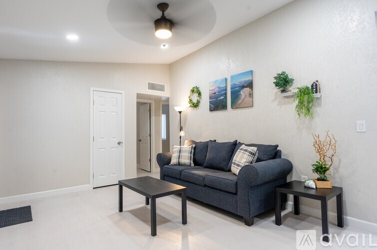 A living room with a grey couch, a black coffee table, and a ceiling fan.