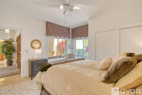 A bedroom with a large bed and a ceiling fan.