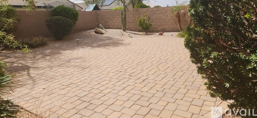 A backyard with a brick patio and a wall.