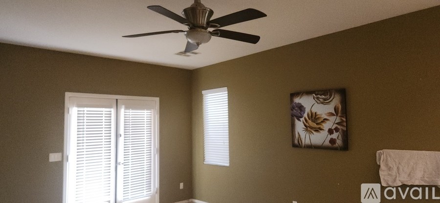 A room with a ceiling fan and a picture on the wall.