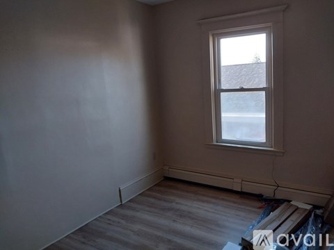 A room with a window and wooden flooring.
