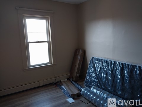 A room with a window and a blue couch covered in plastic.